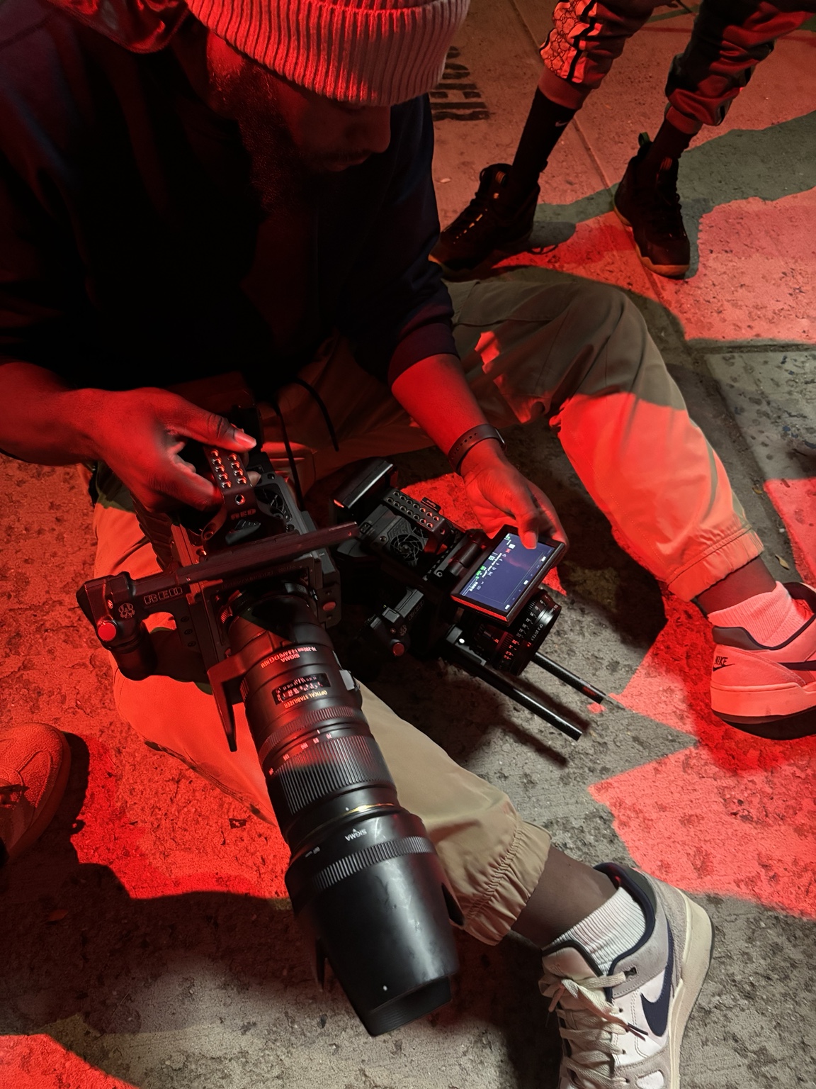 Crew member adjusting a cinema camera under red set lighting