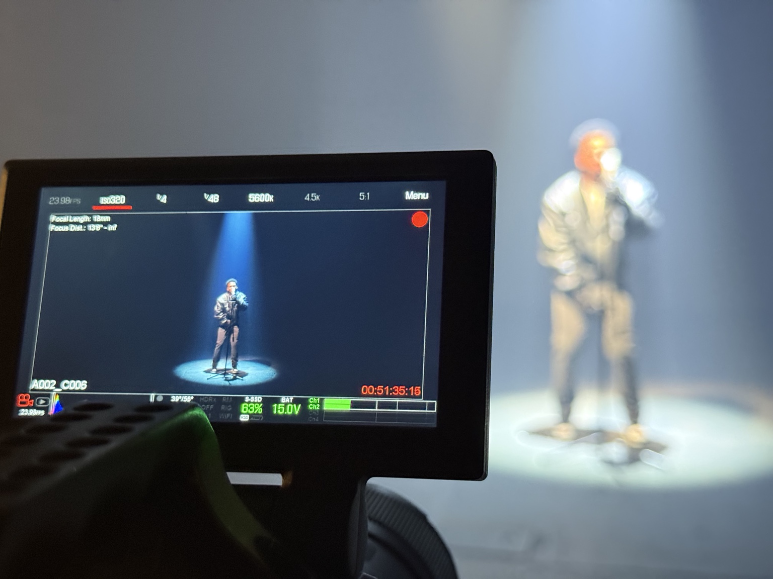 Camera monitor framing an artist performing under a spotlight